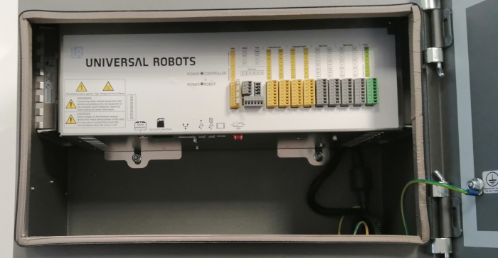 Inside the controller we can see various connectors and cables exposed. The right side includes I/O and safety, at the bottom USB, HMI and SD card.