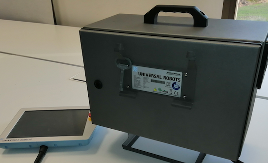 A) Universal Robots UR3 robot CB3.1 controller and associated teach pendant (HMI). The controller has a mechanical lock aimed to secure physical access.